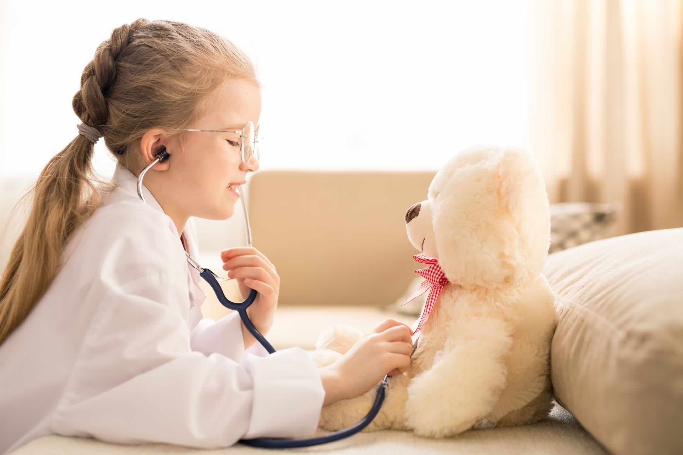 Kind mit Stethoskop untersucht ein Kuscheltier – Kindernarkose