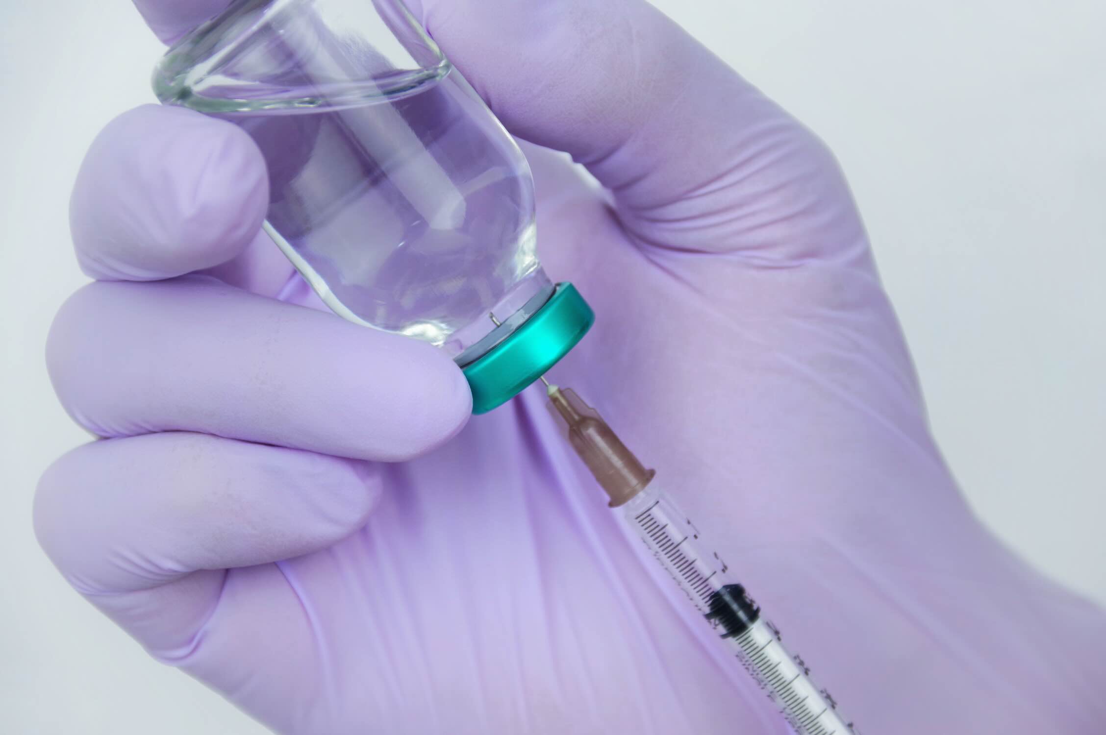 Ampulle und Spritze in behandschuhten Händen – Regionalanästhesie